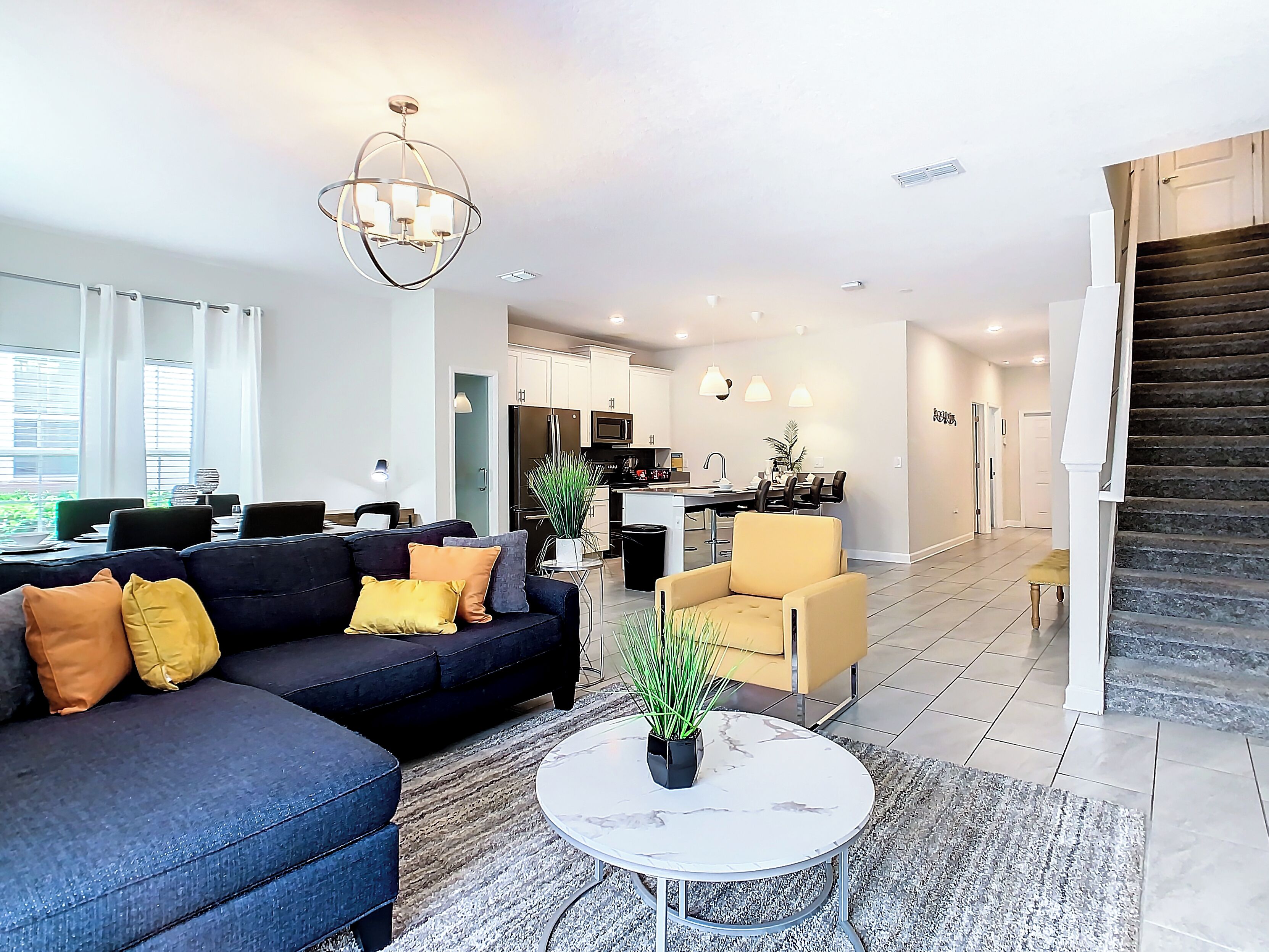 A modern living room with a dark sofa, a round coffee table, and a dining area with a table and chairs.