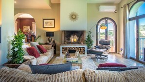 A spacious living room with a fireplace, comfortable seating, and large windows offering a view of the outdoors. - Luxury Villa - Sleeps up to 8 & Infinity Pool (Estepona)