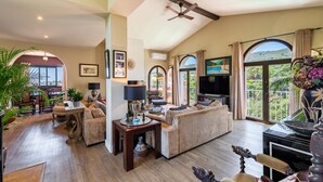A spacious living room with a fireplace, comfortable seating, and a large window offering a scenic view. - Luxury Villa - Sleeps up to 8 & Infinity Pool (Estepona)