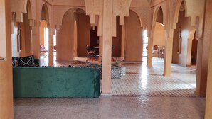 A spacious interior with arches, a patterned rug, and a green sofa. - Hotel Kasbah Riad Amnir (M'Hamid El Ghizlane)