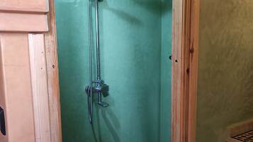 Un baño pequeño y estrecho con ducha y retrete.
