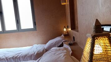 A bedroom with a bed, a nightstand, a lamp, and a window.