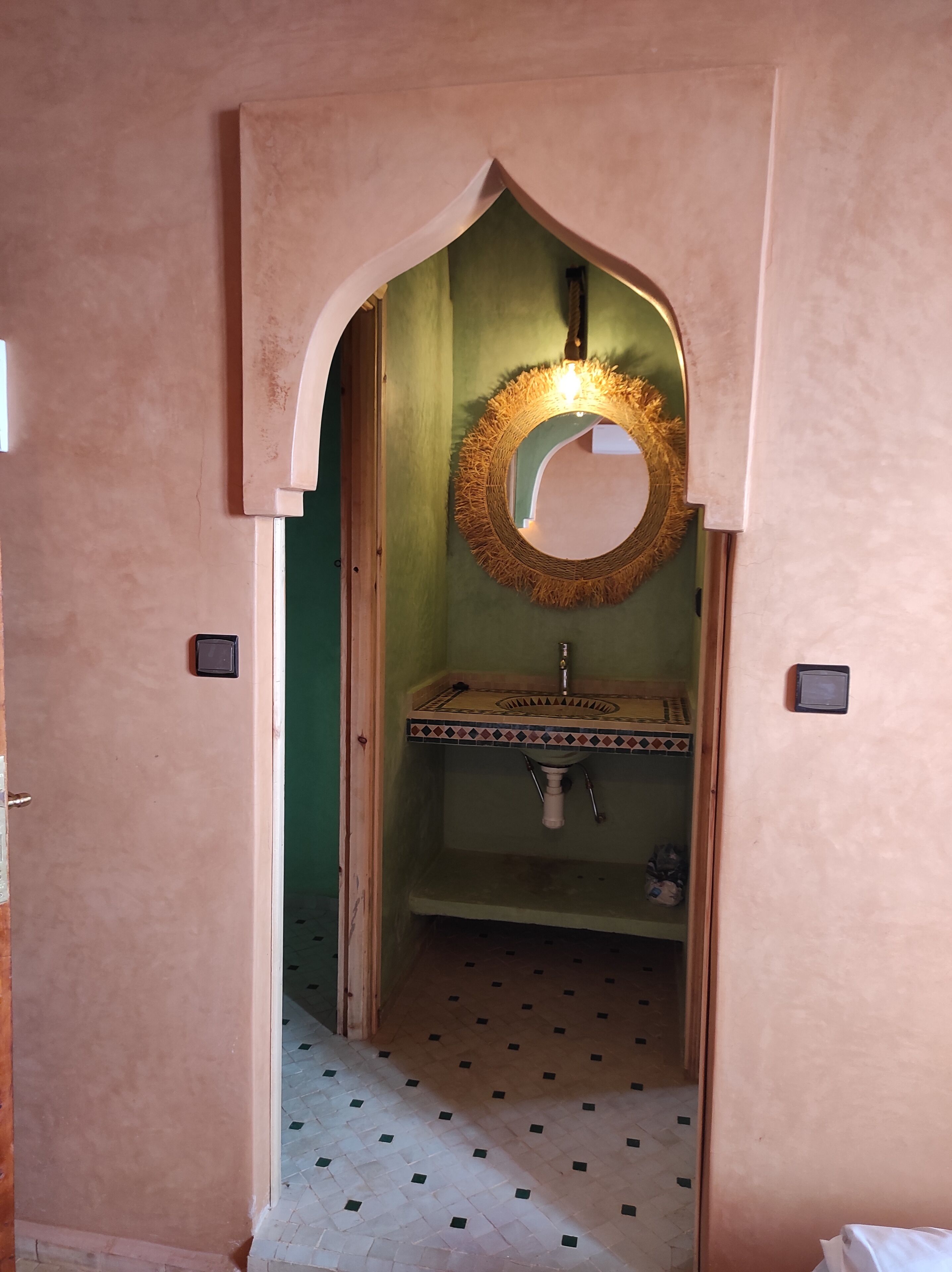 Ein Badezimmer mit einem Waschbecken, einem Spiegel und einem gemusterten Boden.