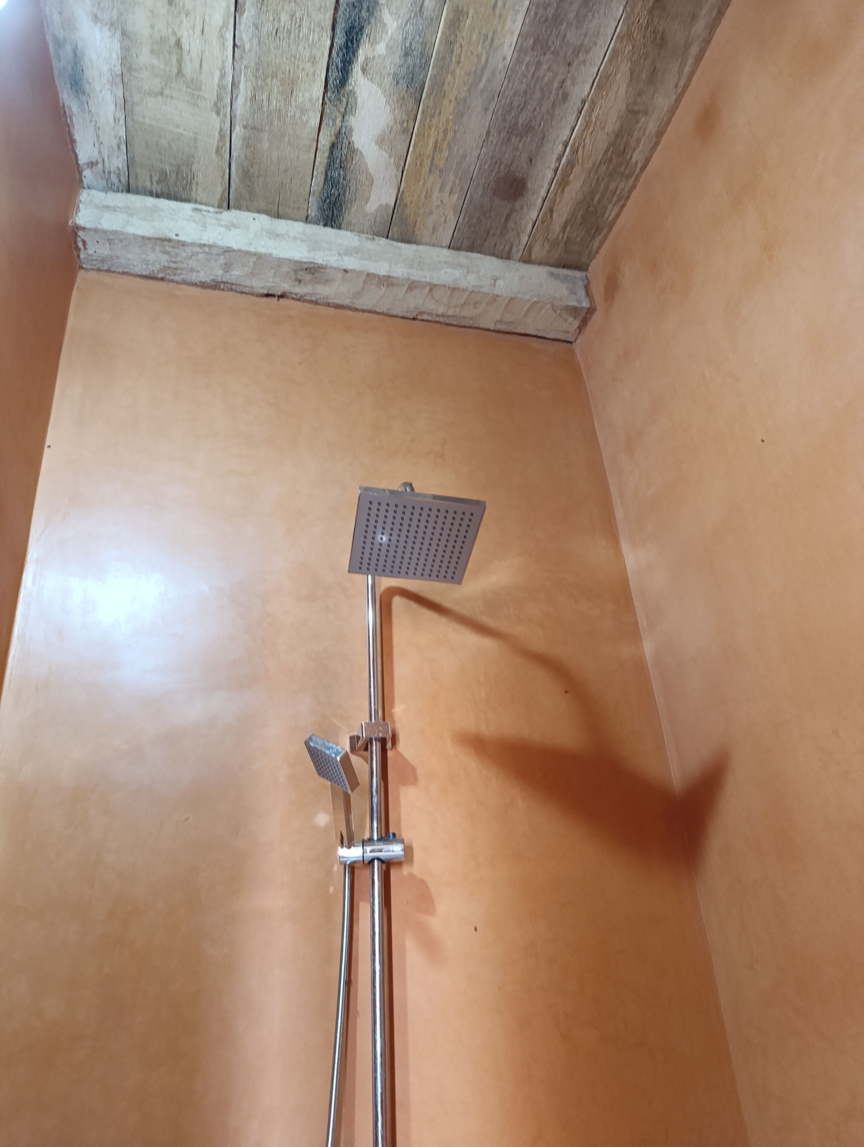 A shower with a handheld showerhead and a fixed showerhead mounted on a wall.
