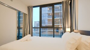 A hotel room with a large bed, a window with curtains, and a view of a building. - City Serenity: 2BR Apt with Pool, Gym, Steam&Sauna (Adelaide)