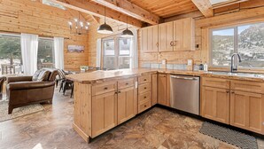 Une cuisine spacieuse dotée de meubles en bois, d’un îlot central et d’une grande fenêtre offrant une vue sur l’extérieur.