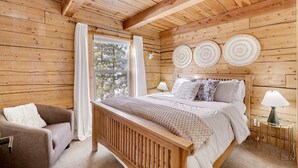 Une chambre dans une cabane en bois, avec un lit, une chaise et une table de chevet.
