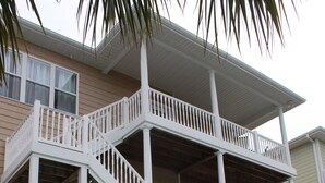 A multi-story building with a pool, featuring a white exterior, multiple balconies, and a covered outdoor area.