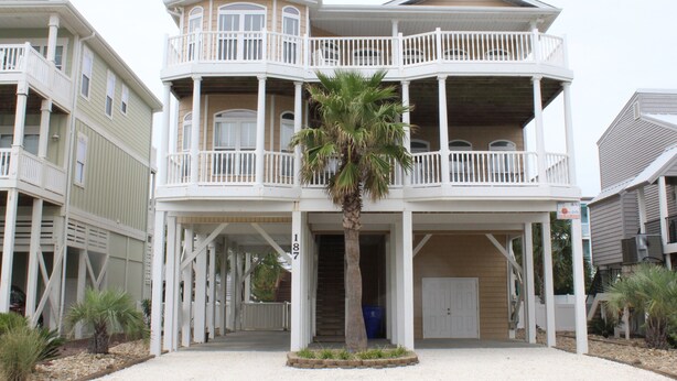 A multi-story building with balconies and a central palm tree.