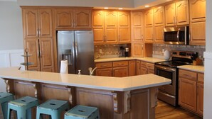 A kitchen with wooden cabinets, stainless steel appliances, and a central island with stools.