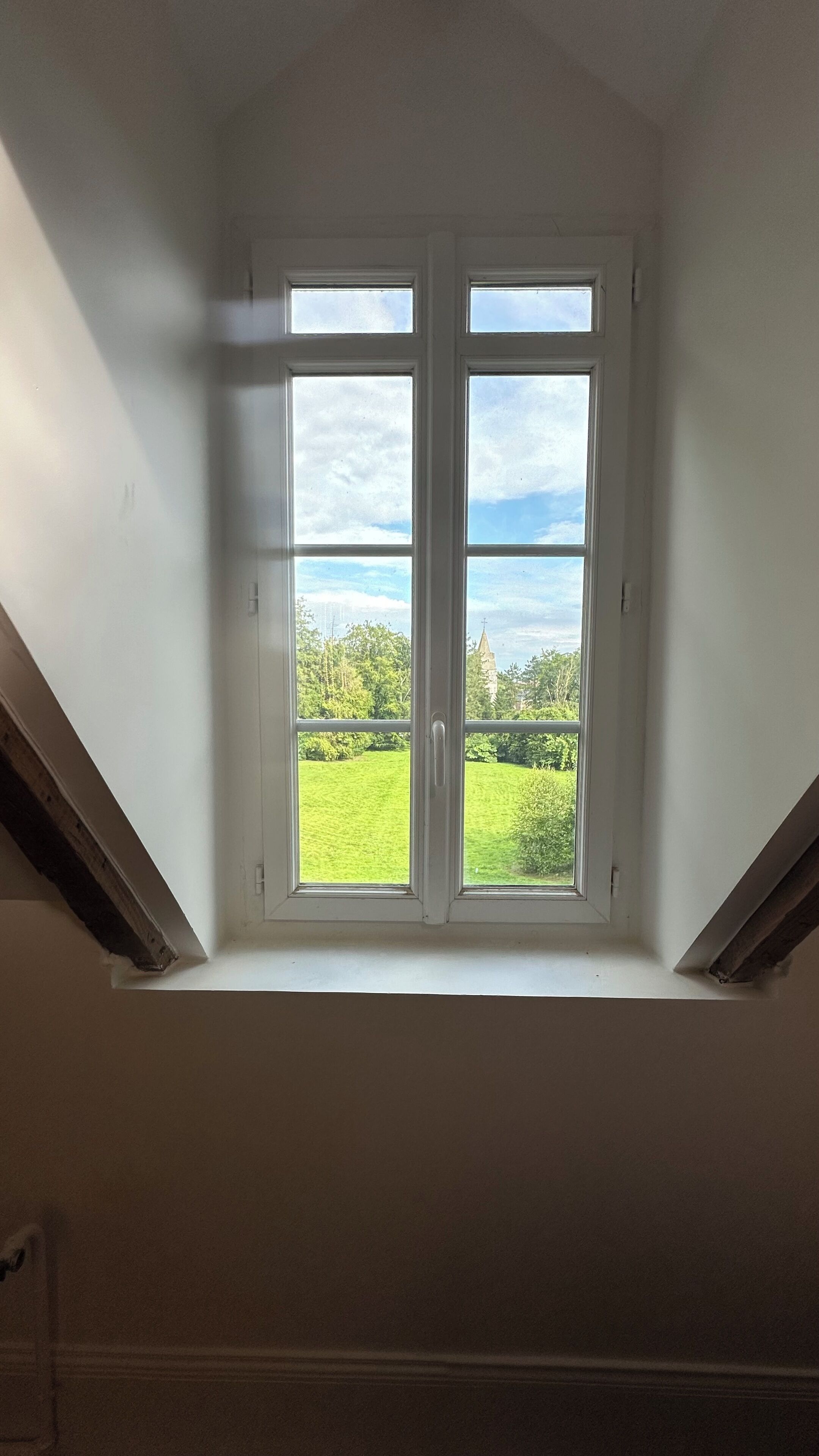 Ein Dachbodenschlössel mit Blick auf ein grünes Feld und ein entferntes Gebäude.