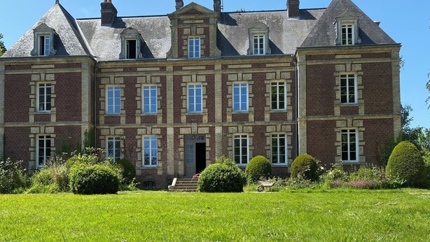 A large, multi-story building with a symmetrical facade, featuring a central entrance with steps, flanked by windows and a small garden area with a single daisy in the foreground. - Chateau Loyd&Spa Normandie Pays de Caux (Les Hauts-de-Caux)