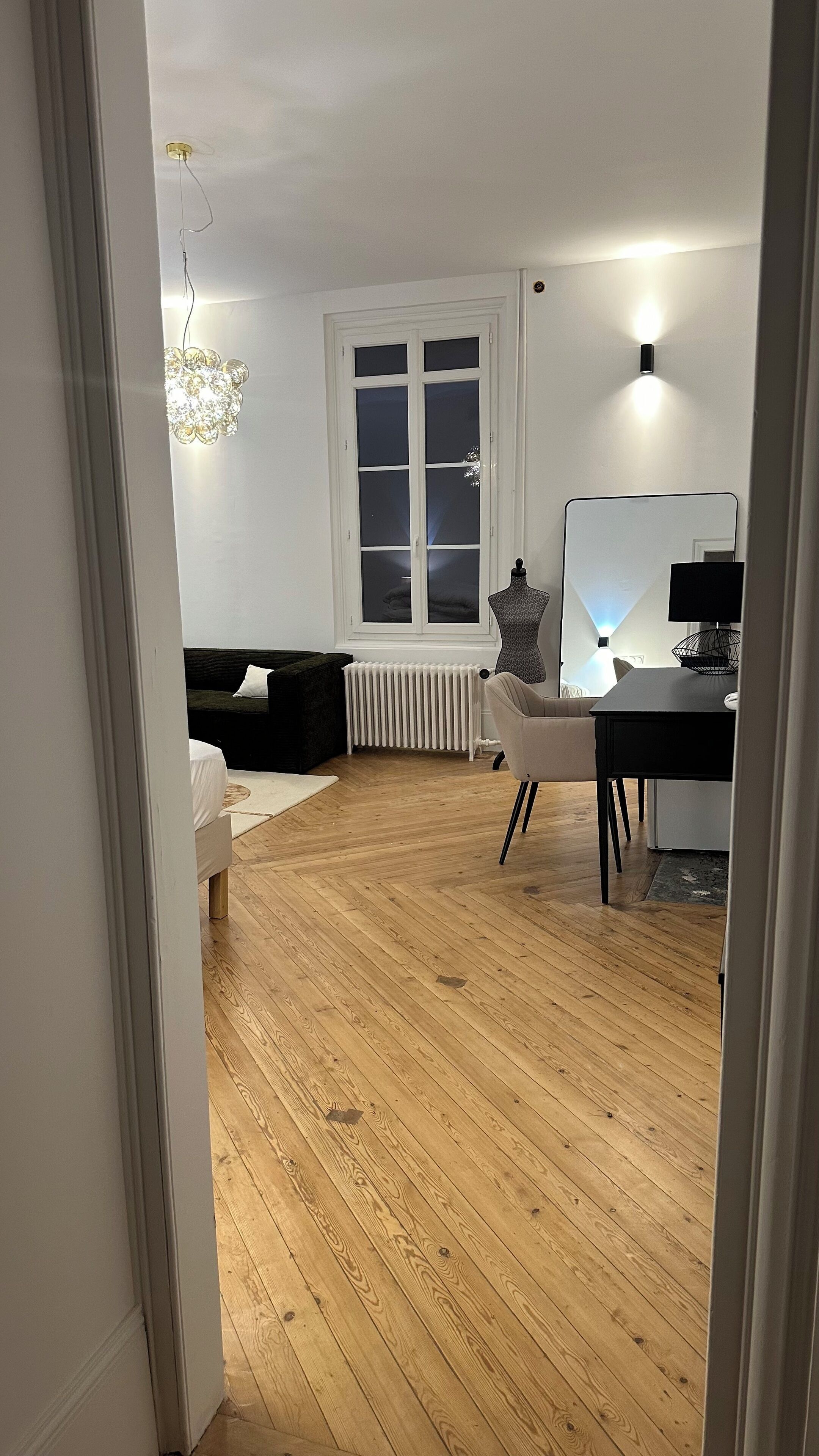 A room with a bed, a desk, a radiator, and a window.