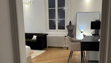 A room with a bed, a desk, a radiator, and a window.