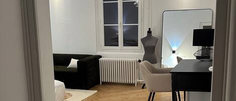 A room with a bed, a desk, a radiator, and a window.