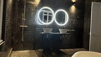 Ein modernes Badezimmer mit einer großen Badewanne, einem doppelten Waschbecken und einer begehbaren Dusche.