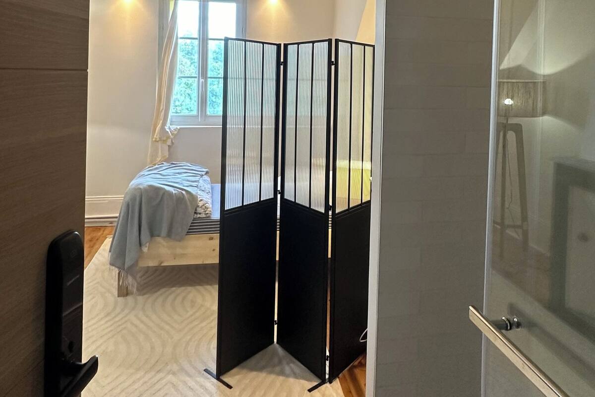 A room with a bed, a partition, a window, and a door.