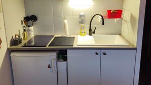 A compact kitchen with a microwave, sink, and a small refrigerator.