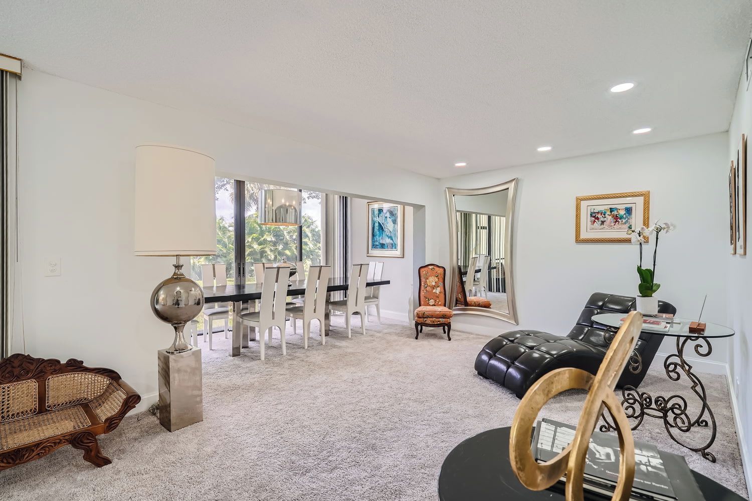 A spacious living room with a dining area, a sofa, a coffee table, and a large mirror.