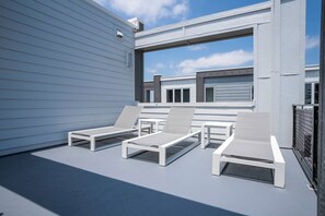 Relax on the rooftop terrace with comfortable lounge chairs and a small table, surrounded by large windows offering views of the surrounding area.