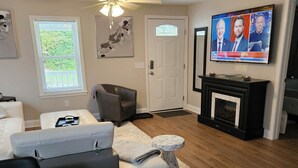 Una sala de estar con chimenea, televisor y comedor con una mesa redonda y sillas.