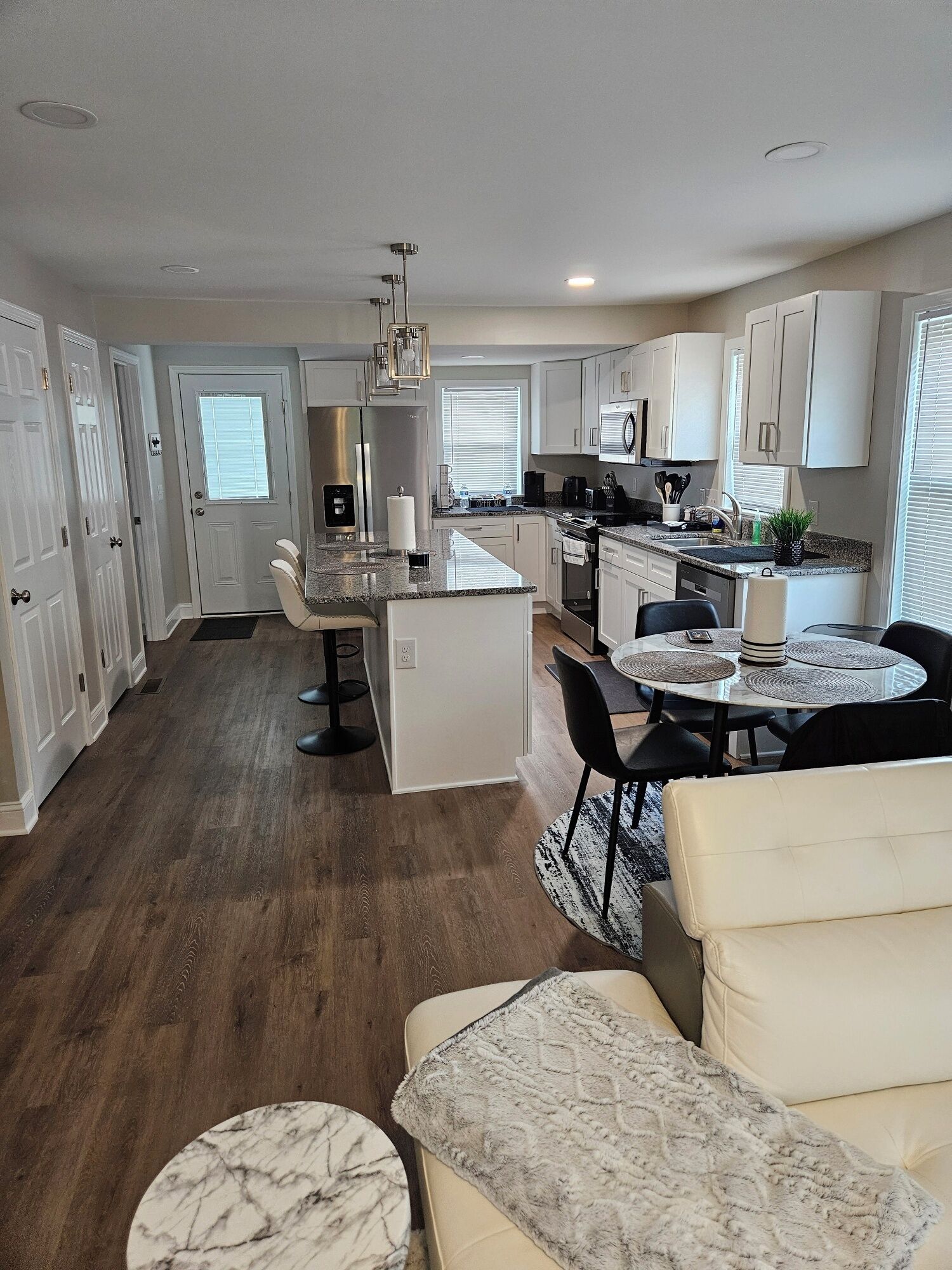 A modern kitchen with white cabinetry, a central island, and a dining area with a round table and chairs.