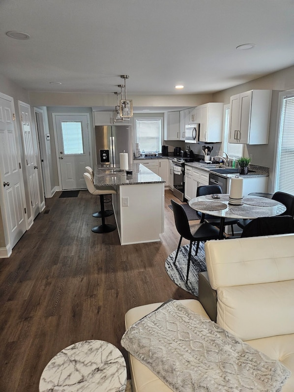 A modern kitchen with white cabinetry, a central island, and a dining area with a round table and chairs.