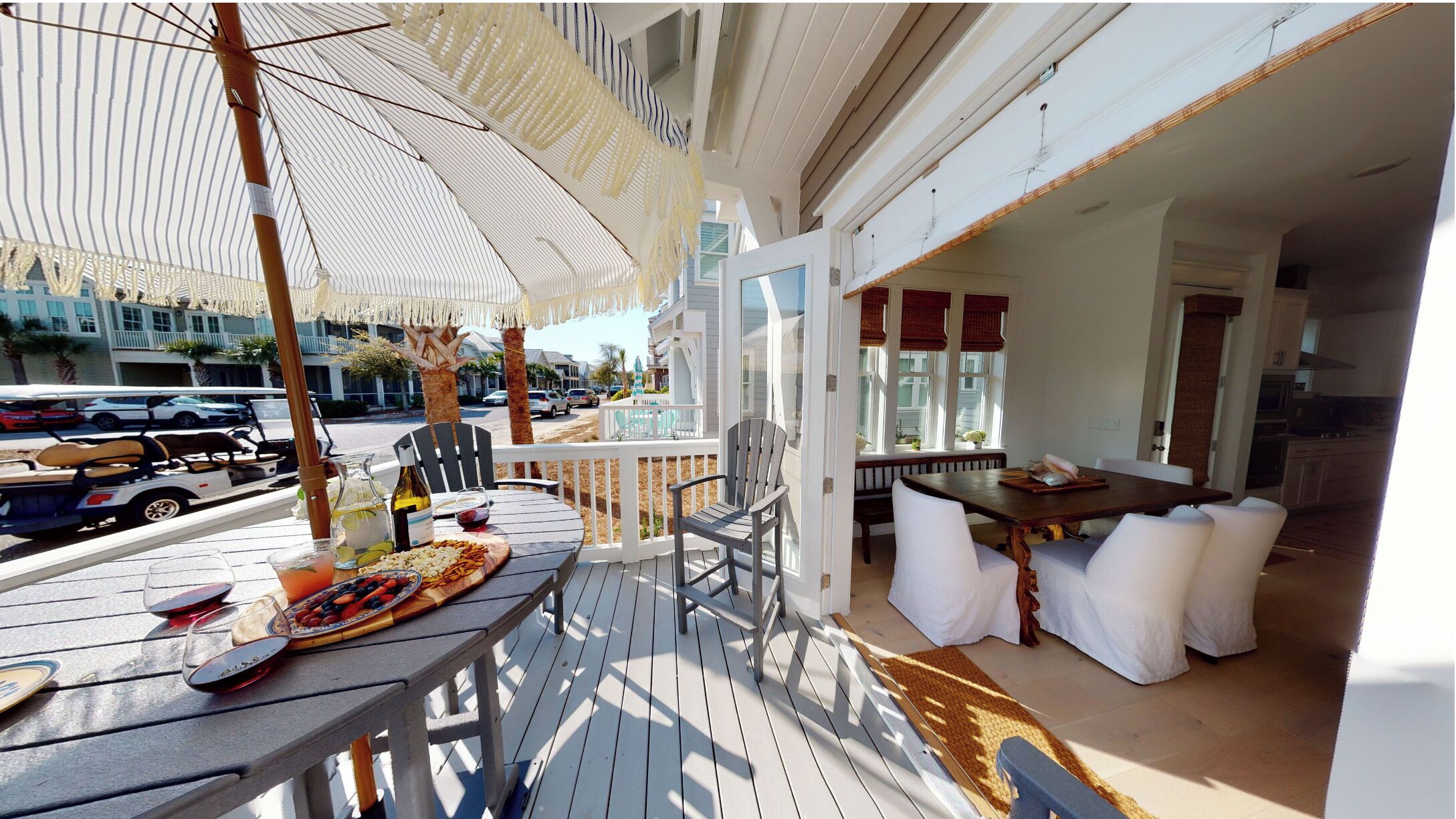 A covered outdoor dining area with a table set for two, chairs, and a wicker umbrella.