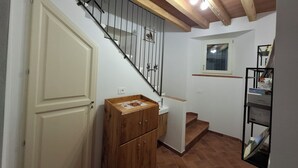 A staircase with a wooden handrail and metal balusters, a small window, and a wooden cabinet with a tiled floor. - Il Castellaro ai Sassi (Guiglia)