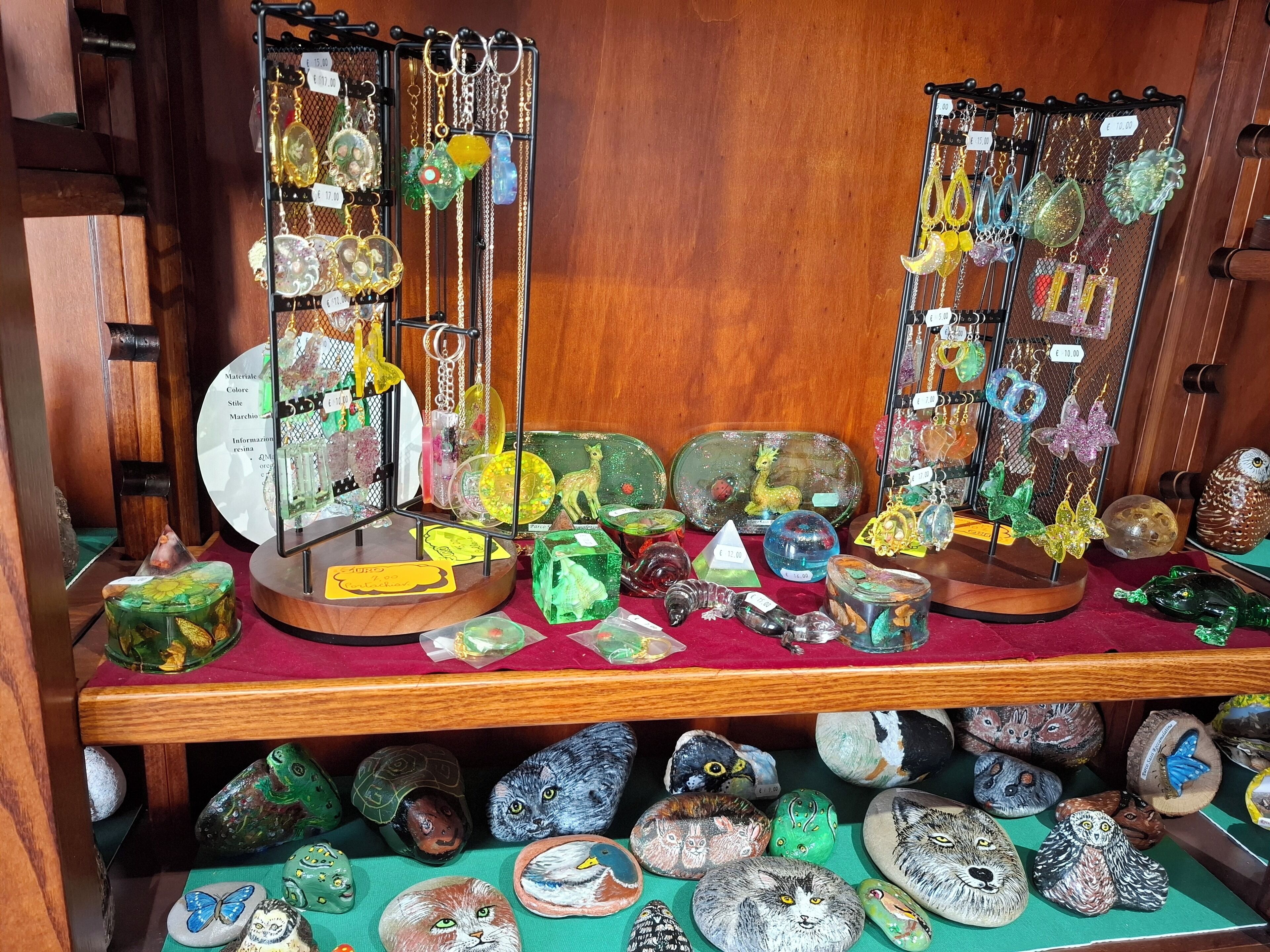 Una exhibición de adornos de vidrio y piedras pintadas sobre estantes.