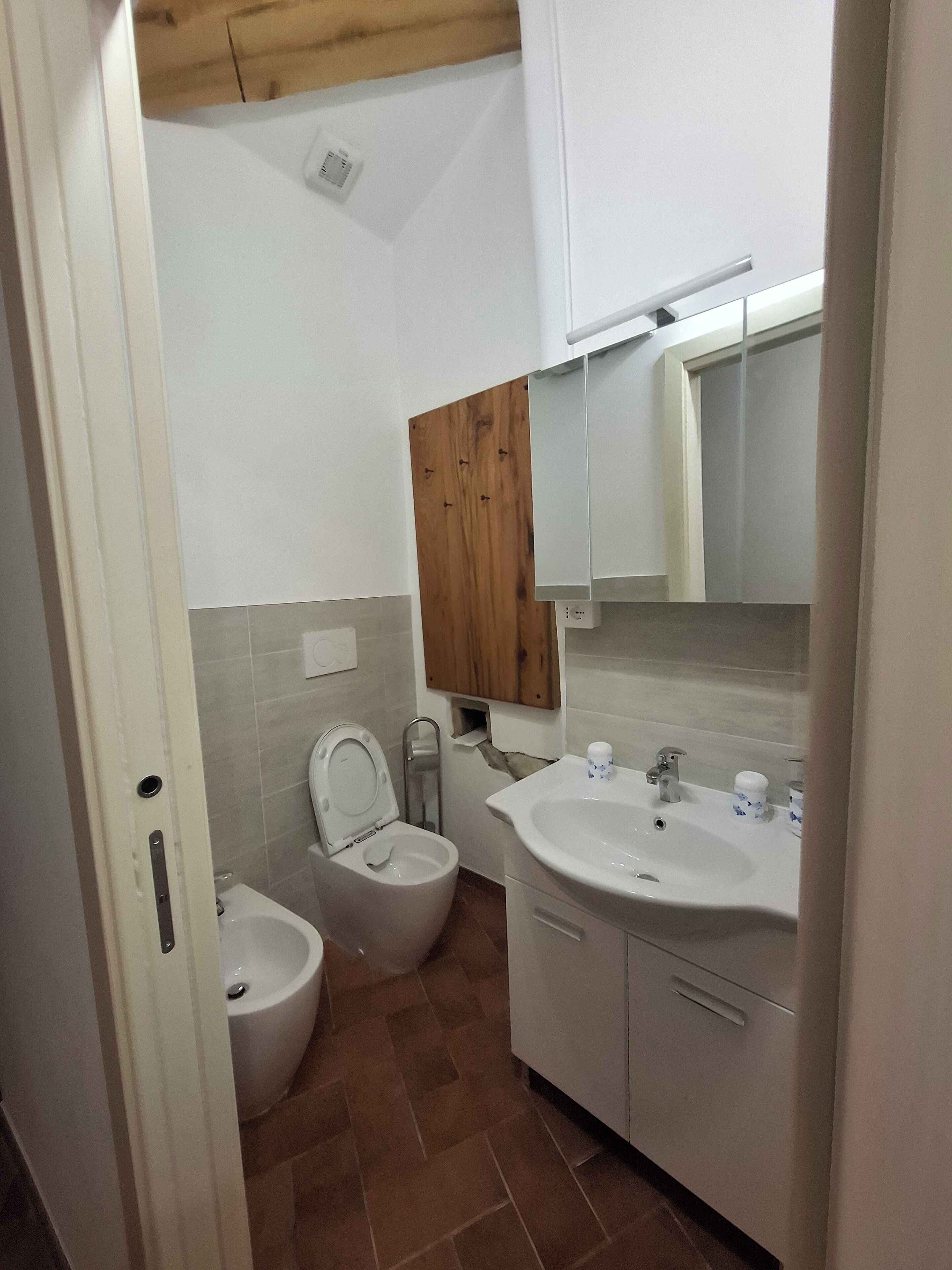 Un baño con inodoro, bidé, lavamanos y un mueble de madera.