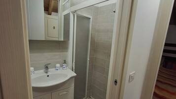 A bathroom with a white sink, mirror, and shower.