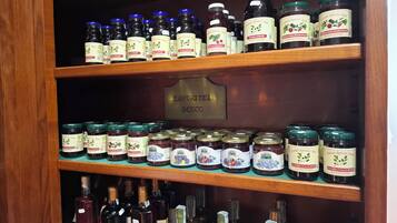 A wooden shelf with various jars and bottles of food products, including preserved fruits and wines.