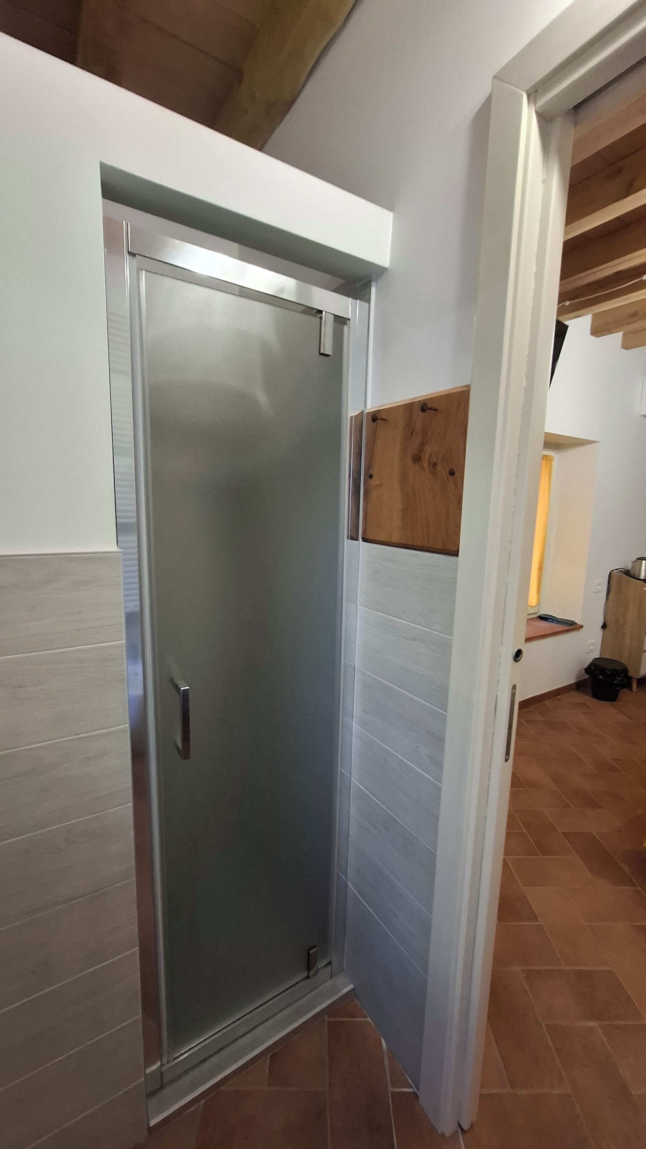 Una stanza con una porta scorrevole, pavimento in legno e parete bianca.