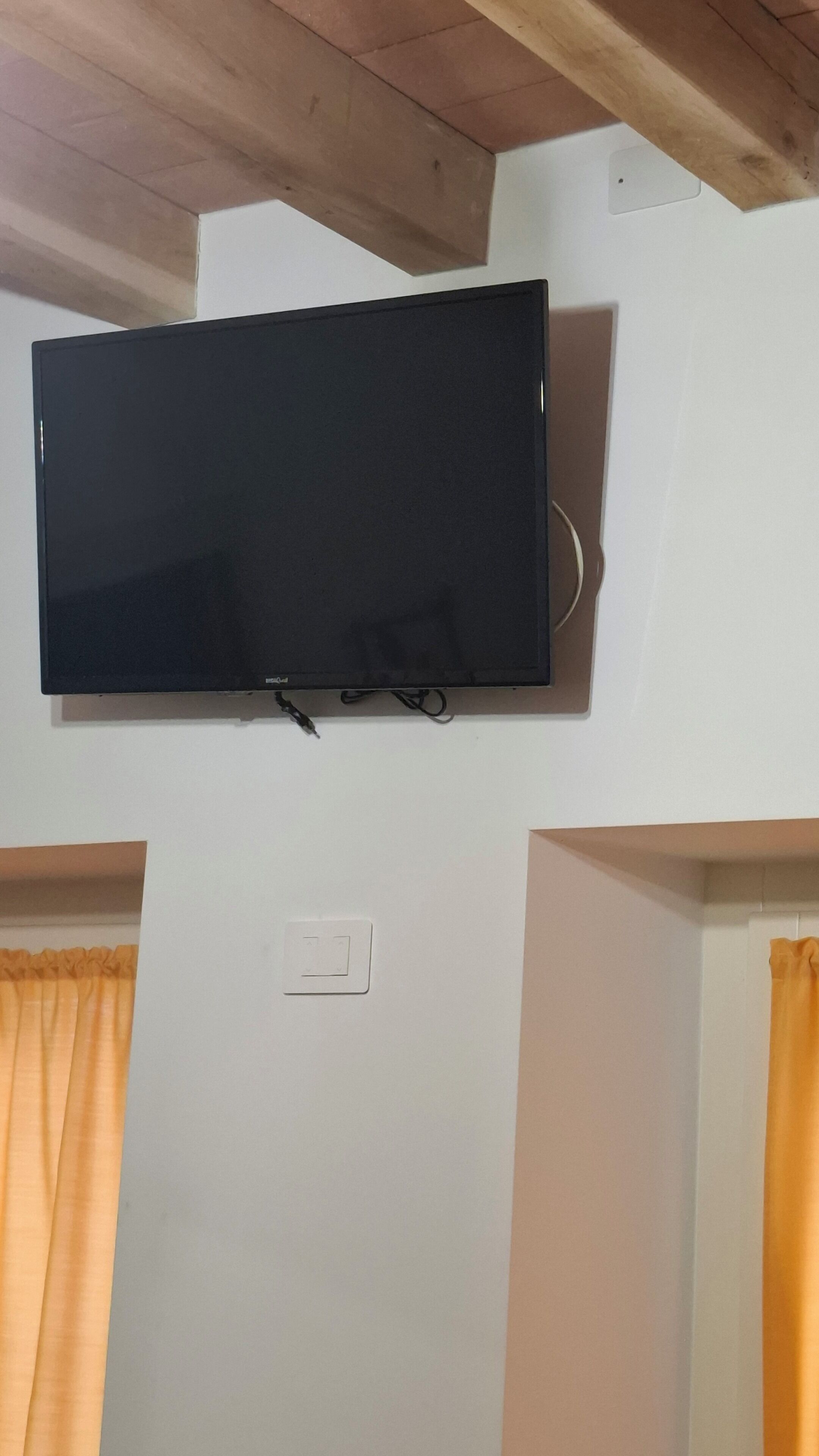 Un televisor de pantalla plana montado en una pared blanca, con un enchufe debajo.