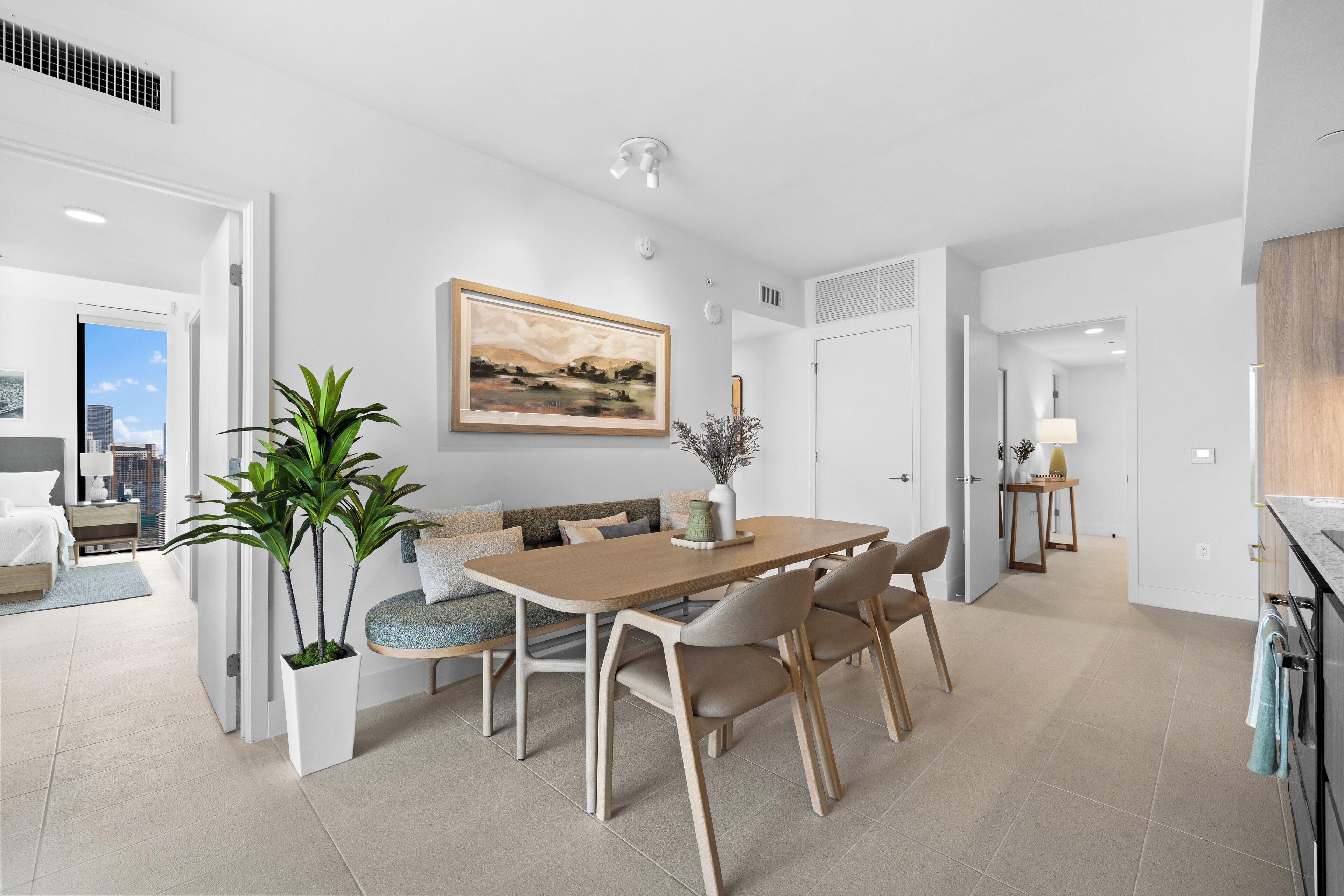 Un comedor moderno con una mesa y sillas de madera, una planta en maceta y un cuadro en la pared.