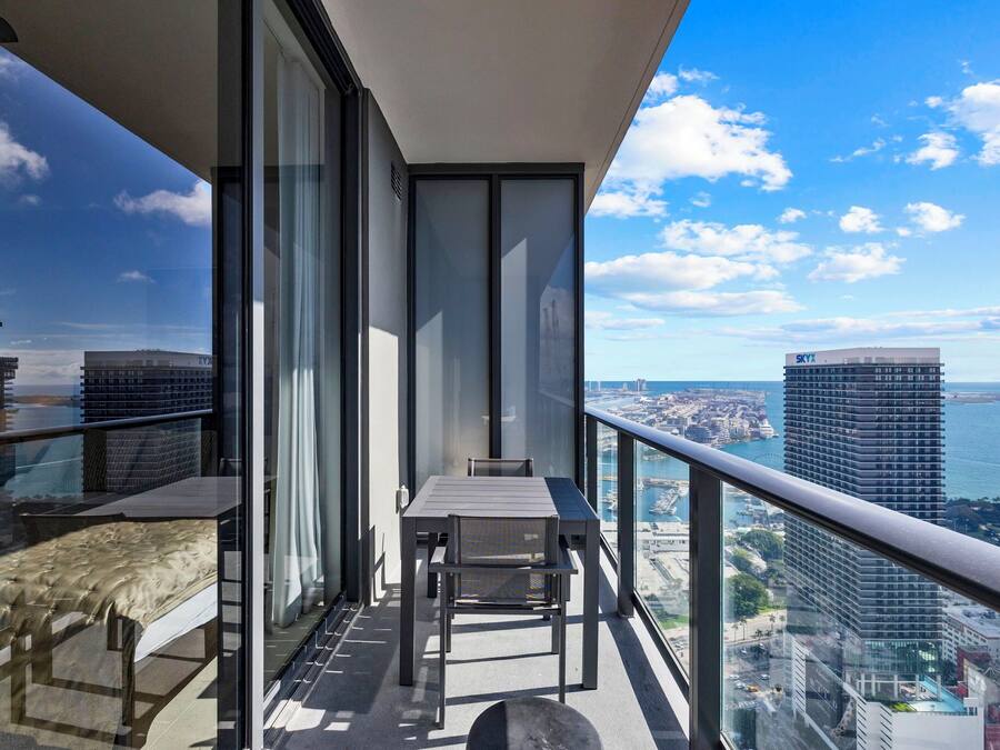Een balkon met een tafel en stoelen, met uitzicht op een stadsbeeld en de zee.