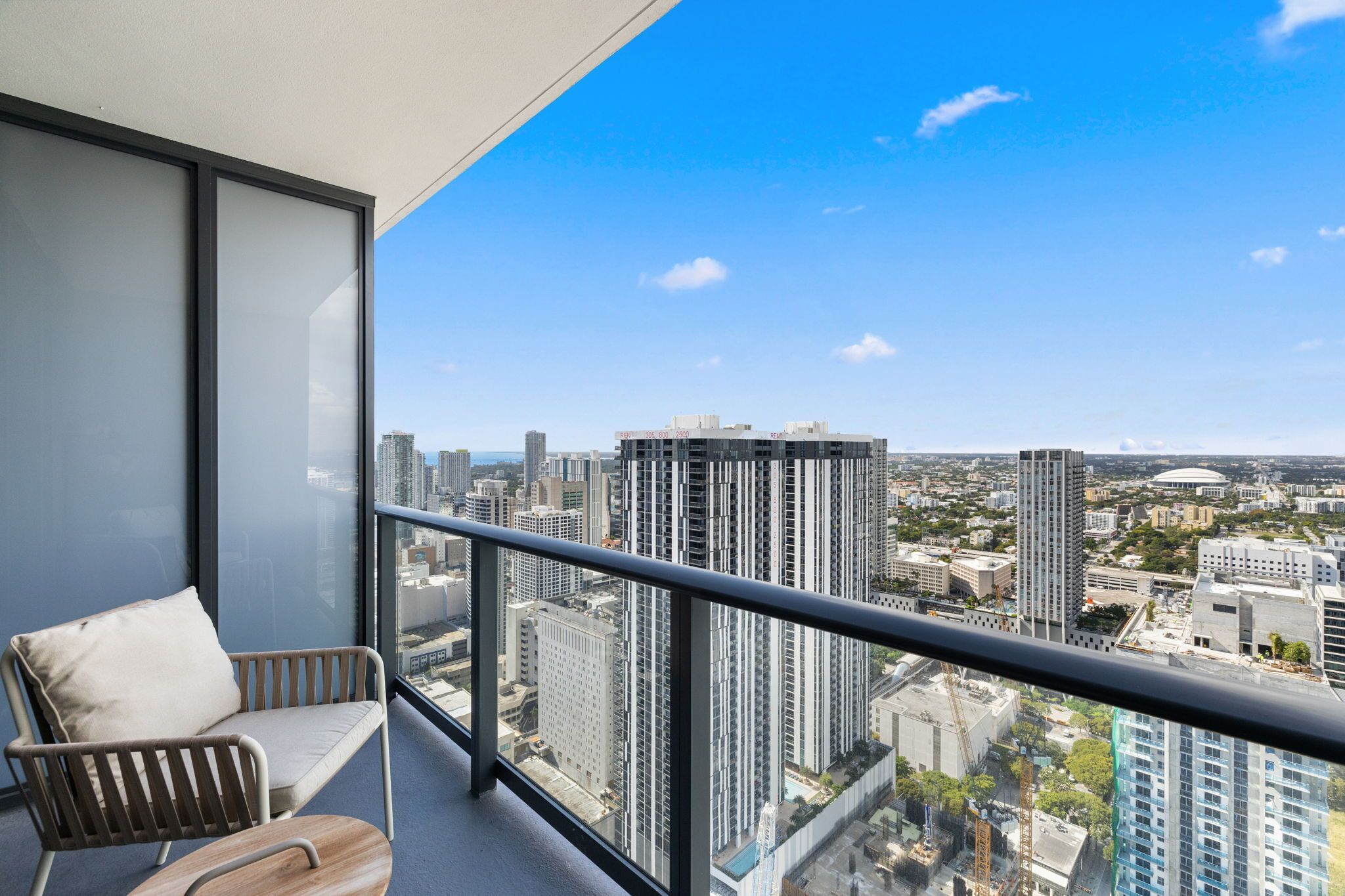Un balcone con vista sulla città, una sedia e un divisorio in vetro.