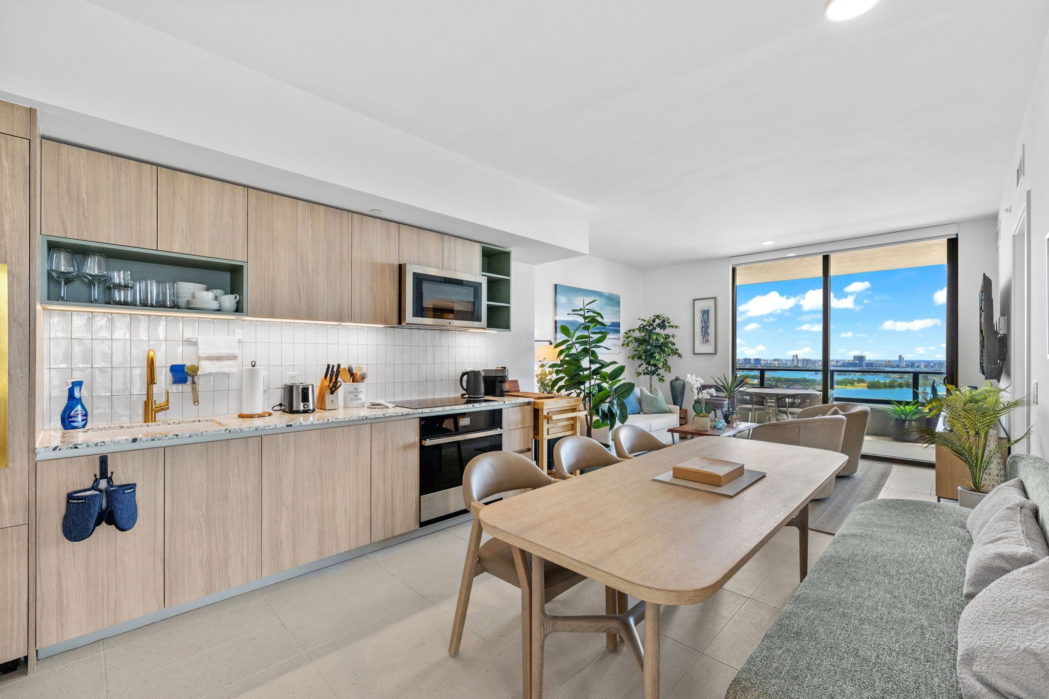 A modern kitchen with a dining area, large windows with a city view, and a cozy seating area.