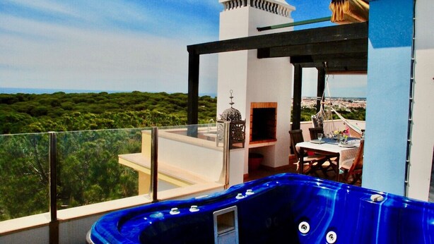 Une terrasse sur le toit avec un jacuzzi, des sièges extérieurs et une vue sur le paysage.