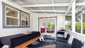 A covered outdoor seating area with a table and benches, a sofa, and a grill. - Your Perfect Hilo Homebase - Sleeps 9 with AC (Hilo)