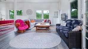 A spacious living room with a sofa, a coffee table, and a wicker chair. - Your Perfect Hilo Homebase - Sleeps 9 with AC (Hilo)