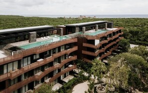 A multi-story hotel with a rooftop pool, balconies, and a view of the sea.