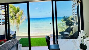 A modern living room with a large glass door leading to a balcony overlooking a beach. - Silver Reef Residencies  (North Side)