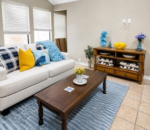A living room with a sofa, coffee table, wooden sideboard, and a vase of flowers. - Country Comfort - Spacious Brownwood Home (Early)