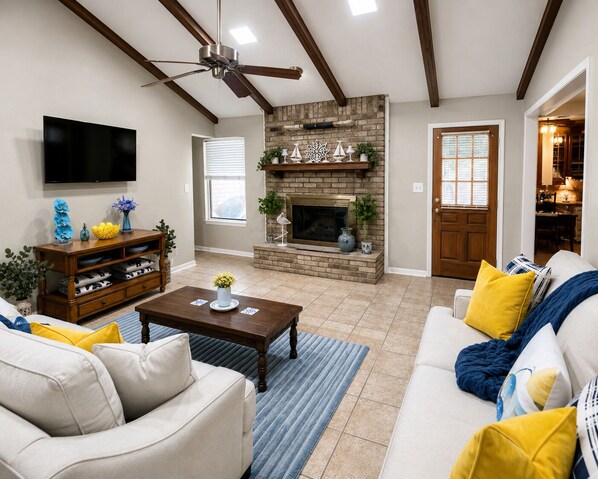 A living room with a fireplace, a ceiling fan, and a television. - Country Comfort - Spacious Brownwood Home (Early)