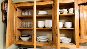 A kitchen with wooden cabinets, a stove, and various dishes and glasses. - Country Comfort - Spacious Brownwood Home (Early)