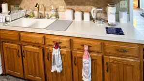 A kitchen with wooden cabinets, a sink, and various kitchen appliances. - Country Comfort - Spacious Brownwood Home (Early)