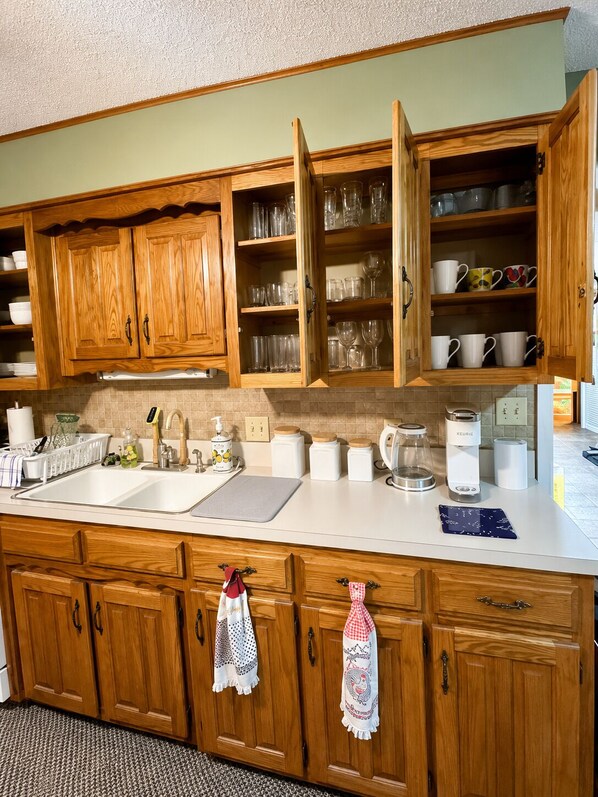 A kitchen with wooden cabinets, a sink, and various kitchen appliances. - Country Comfort - Spacious Brownwood Home (Early)
