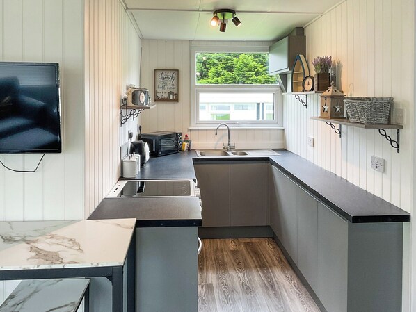 A compact kitchen with a built-in microwave, a sink, and a window providing a view of greenery outside.